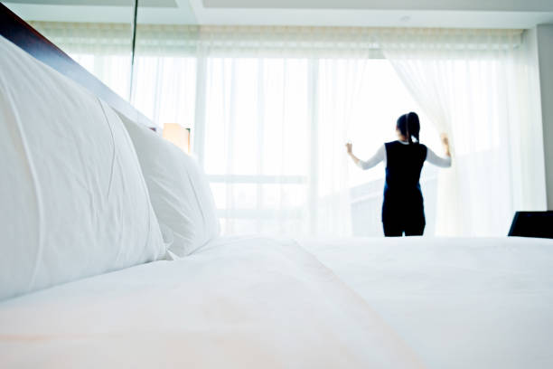 Young asian woman standing and looking out the window in hotel room.
