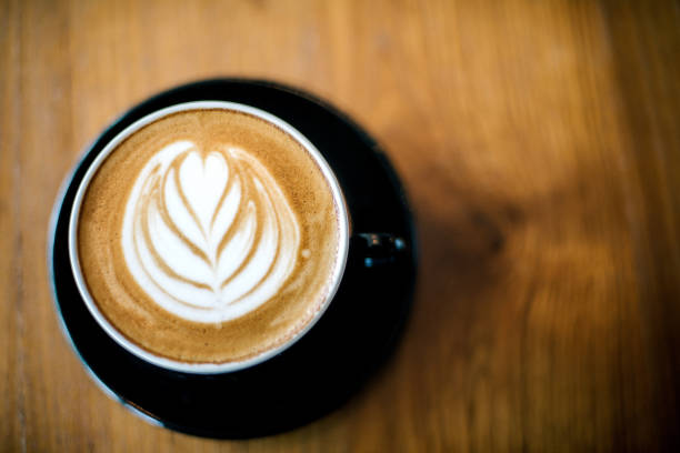 istock Latte art on dark grained wood top view 826771058