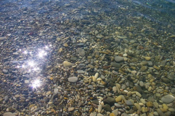 istock sea pebble beach with multicoloured stones, waves with foam 826771934
