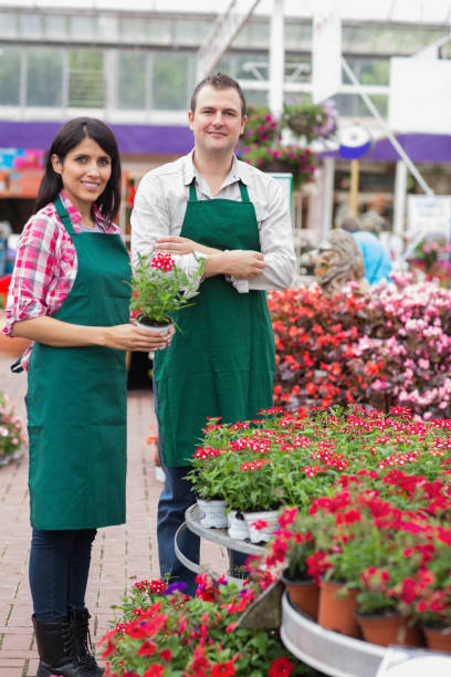 istock Two garden center workers with one holding flower pot 826777780