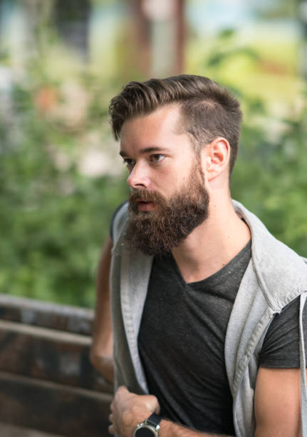 istock Attractive thoughtful bearded guy sitting on a bench in park 826778740