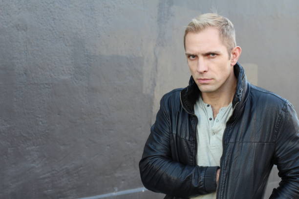 Man pulling something out of his jacket Suspicious blond man pulling something out of his leather jacket. leather pocket clothing hide stock pictures, royalty-free photos & images