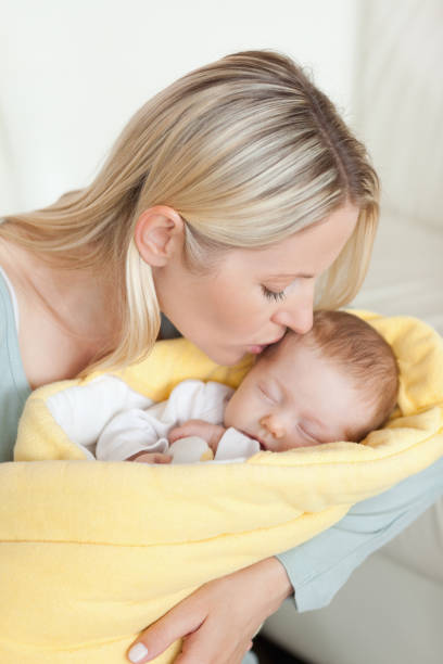 istock Affectionate mother kissing her babys forehead 826789110
