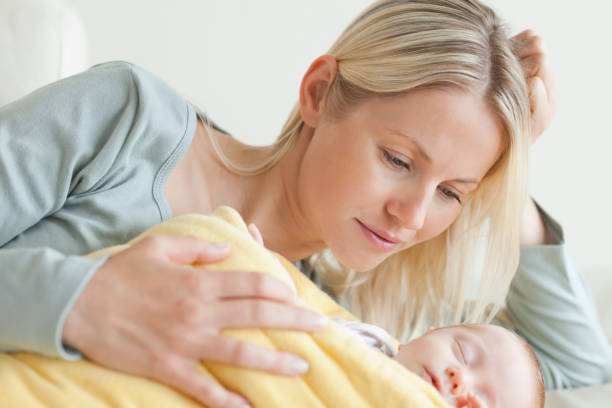 istock Mom relaxing next to her sleeping baby 826789450