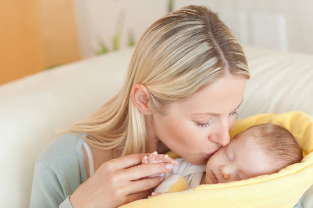istock Mother on the sofa kissing her baby 826793018