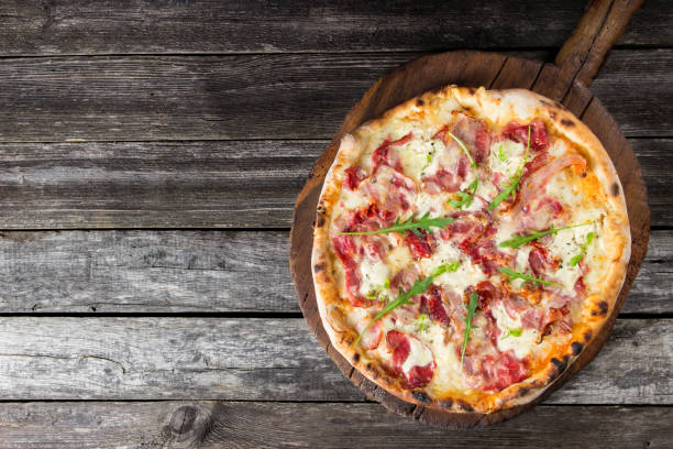 istock Pizza on the rustic wooden background with blank space 826793224