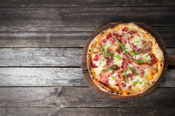 istock Pizza on the rustic wooden background with blank space 826795528