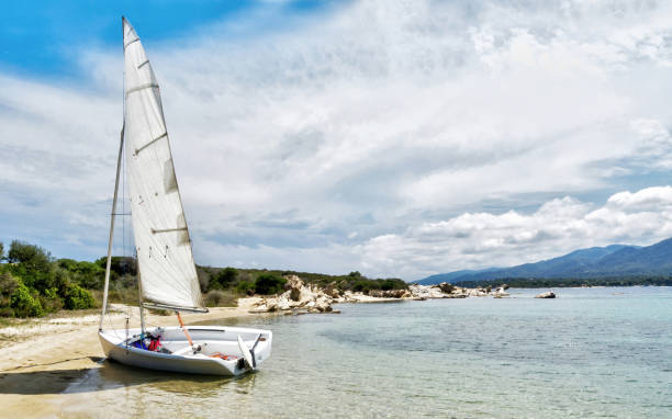 White small Sailboat on Vourvourou Beach in Halkidiki, Greece White small Sailboat on Vourvourou Beach in Halkidiki, Greece. halkidiki beach stock pictures, royalty-free photos & images