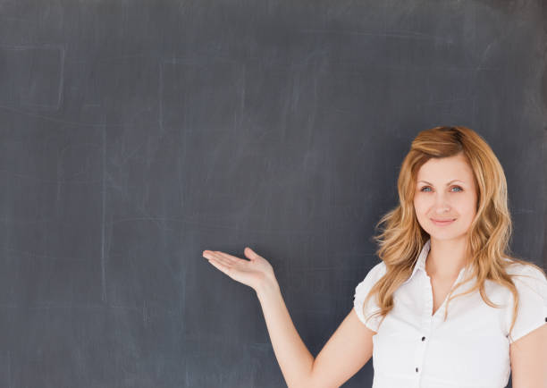 istock Cute female teacher showing an empty blackboard 826803116