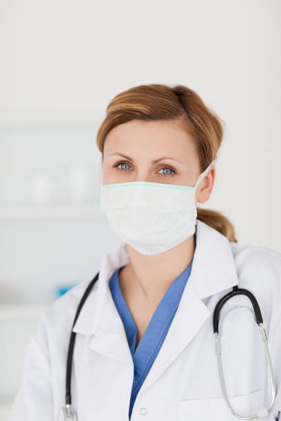 istock Blondhaired scientist with a mask and a stethoscope posing 826803668