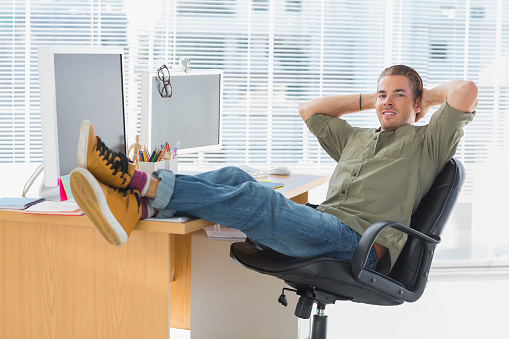 Designer relaxing with foot on the desk in a modern office