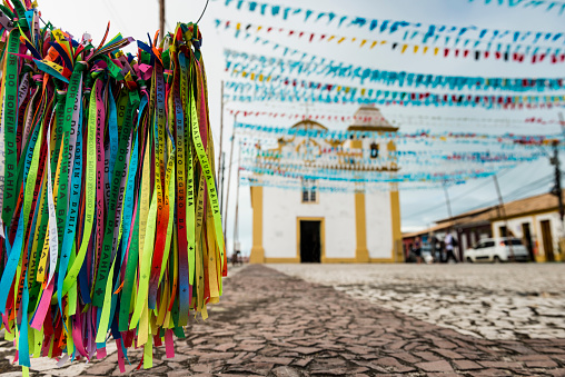 A close-up view of the 'Bonfim' ribbons, colorful decorative flags celebrating the 'Festa Junina' or 'Festa de São João', and the church 'Igreja de Nossa Senhora d'Ajuda', located at the district of Arraial d'Ajuda in Porto Seguro, Bahia state - Brazil