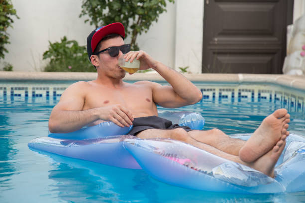 istock Man drinking beer on an air bed in the pool. 826812602