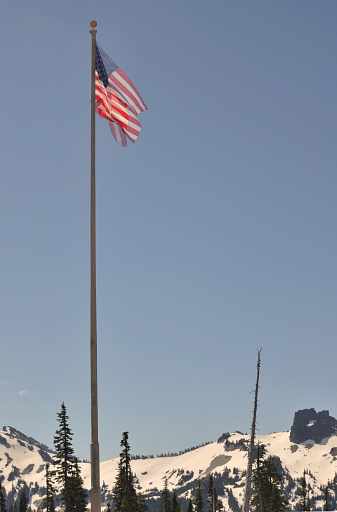 On rock, man in military uniform holding an American flag.