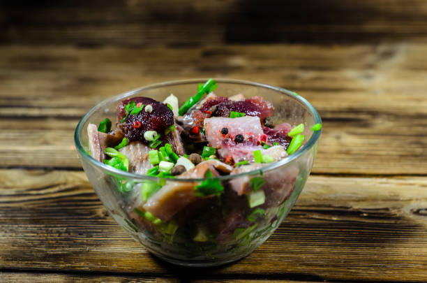 Herring with spices in glass bowl on rustic wooden table