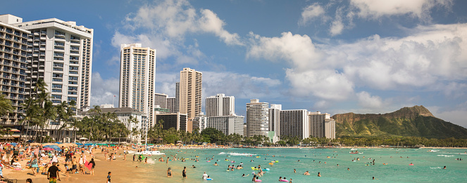 Panoramic of tourists sun bathing and swimming in the Pacific Ocean shore of Waikiki beach in Honolulu, Oahu, Hawaii