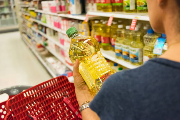 Shopping for cooking oil Caucasian housewife shopping for vegetable oil in a supermarket alley cooking oil stock pictures, royalty-free photos & images