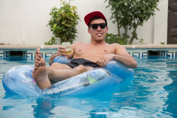 istock Man drinking beer on an air bed in the pool. 826840788
