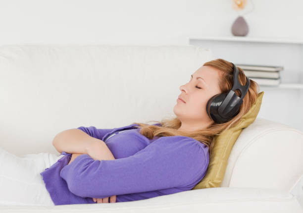 istock Good looking redhaired woman listening to music while taking a rest lying on a sofa 826841030