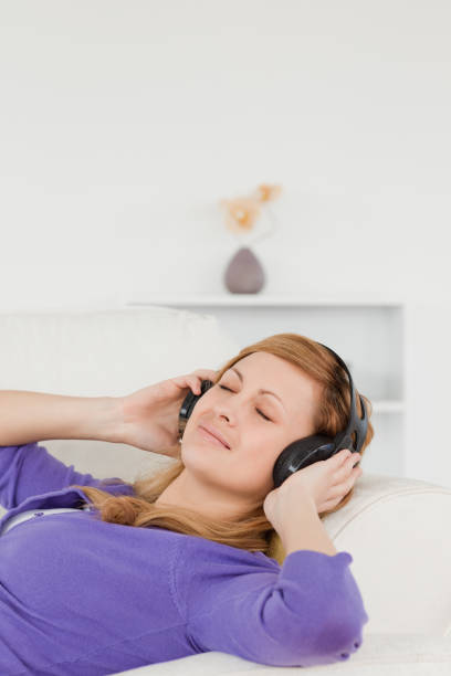 istock Beautiful redhaired woman listening to music while taking a rest while lying on a sofa 826841074