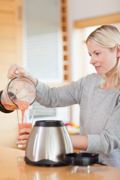 istock Side view of woman pouring self made smoothie 826854762