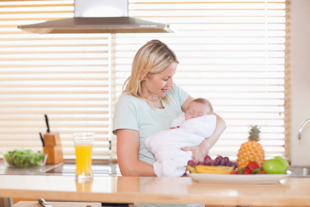 istock Woman holding her sleeping baby in the kitchen 826854994