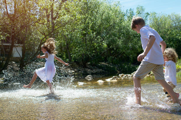 Children running over a ford with clear mountain stream water on a hot day with water splashing Stellenbosch Cape Town South Africa