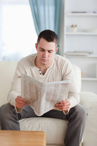 istock Portrait of a young man reading a newspaper 826860012