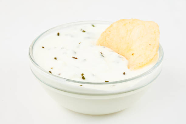istock Bowl of white dip with herbs and a nacho dipped in it 826876016