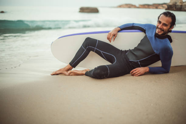 istock Surfer man sitting on the beach 826878206
