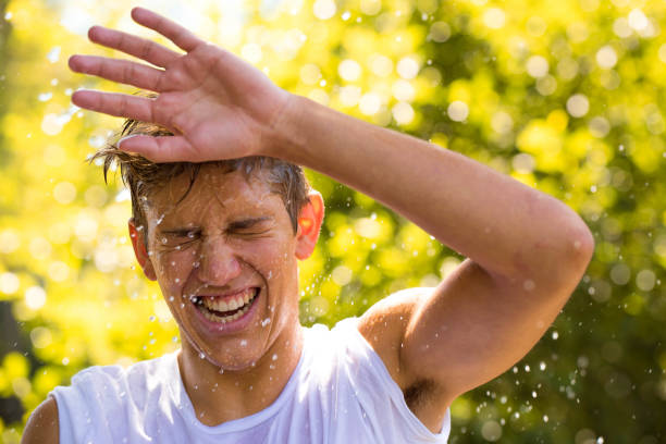 istock Young man with splashing water in his face 826888560