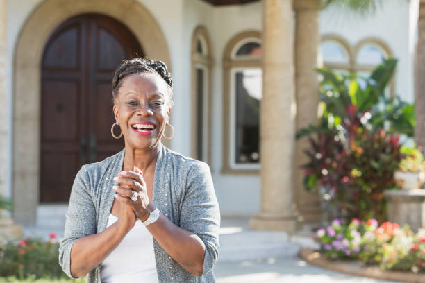 mujer senior afroestadounidense de pie delante de casa - upper class wealth women senior adult fotografías e imágenes de stock