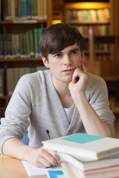 istock Man sitting at library desk and thinking 826910852