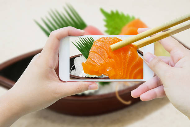 istock chopsticks hold salmon sashimi in mobile phone 826925236