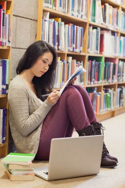 istock Student leaning at the wall sitting on library floor 826929120