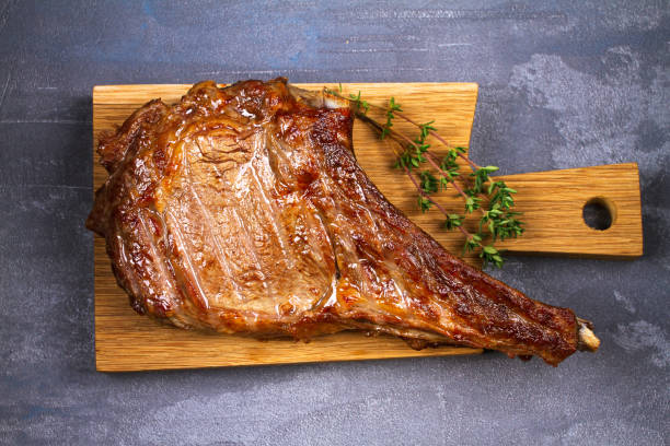 istock Rib Eye Beef Steak with Thyme on Chopping Board. View from above, top studio shot 826929696