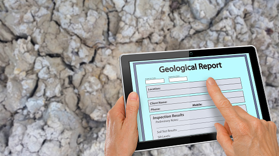 Completar en línea Informe geológico en una tableta de ordenador - enfrente del fondo del suelo de arcilla de la mano photo