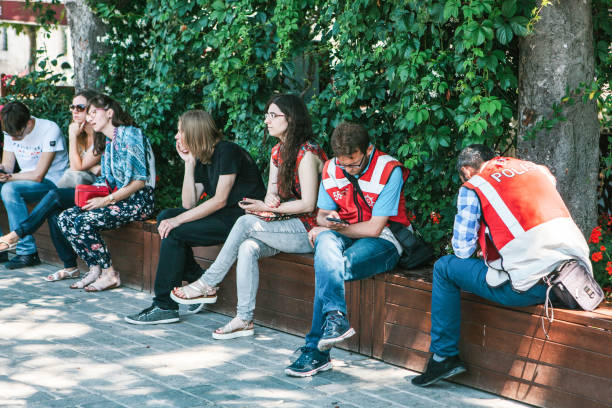 estambul, 15 de junio de 2017: dos turcos turismo policías en el cuadrado, con grupo de personas sentadas cerca de sultanahmet. - vine fotografías e imágenes de stock
