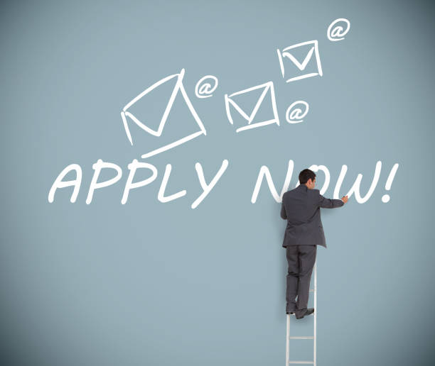 istock Businessman on ladder writing apply now message 826974256
