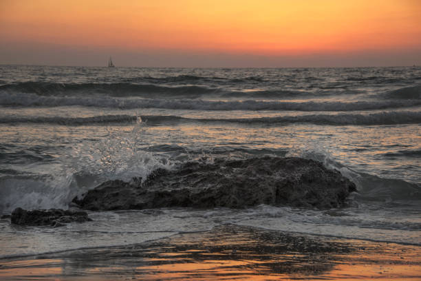 Waves cashing at sunset against a bolder in Israel