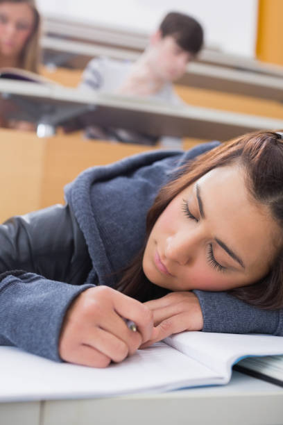 Woman leaning at the desk sleeping Woman leaning at the desk sleeping at the lecture hall male college student sleeping through lecture stock pictures, royalty-free photos & images