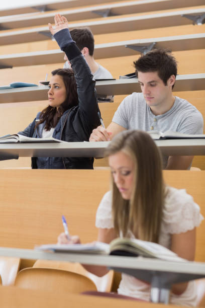 istock Student sitting at the lecture hall with hand up 826990454