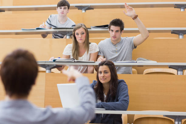 istock Students sitting at the lecture hall with man raising hand to ask question 826990866