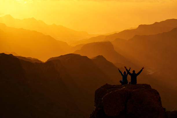hikers on top of the mountain peak Grand Canary with arms raised enjoying the silence.