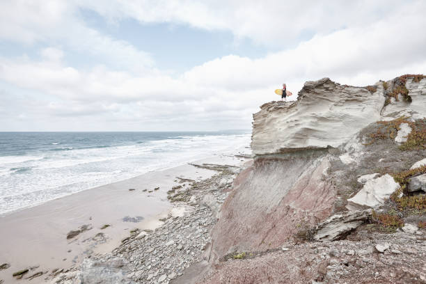 istock Surfer girl on cliff near ocean 827003614