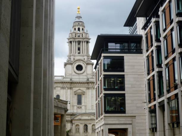 View of St Paul's Cathedral from the buildings of Paternoster Square, London, England St Paul's Cathedral, London, England – August 4, 2017: the photo shows one of the towers of St Paul's Cathedral seen from the buildings around Paternoster Square.  The Cathedral was designed by the architect Sir Christopher Wren, as part of a rebuilding programme following the Great Fire of London (in 1666).  Paternoster Square was historically an area populated by booksellers, but the area's buildings were destroyed in World War II during the Blitz (1940-41); the area was rebuilt in the 1990s, with the works completed in 2003.  The square lies at the heart of the financial district of London, known as 'the City', and contains the London Stock Exchange and numerous offices. paternoster square stock pictures, royalty-free photos & images