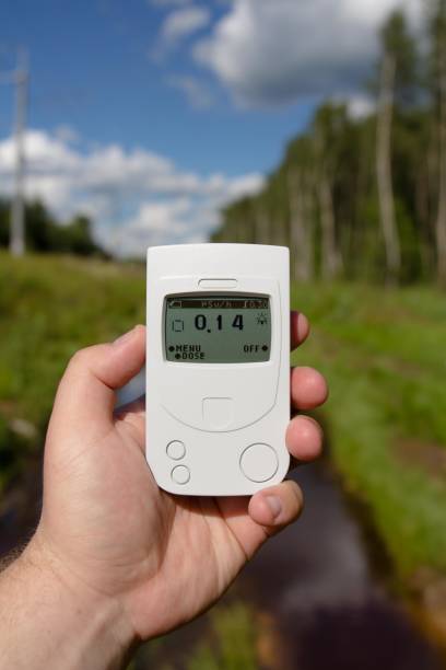 Geiger counter, radiation dosimeter, in hand measuring radiation radiation on a forest clearing with peat puddles. Geiger counter, radiation dosimeter, in hand measuring radiation radiation on a forest clearing with peat puddles. radiation dosimeter stock pictures, royalty-free photos & images