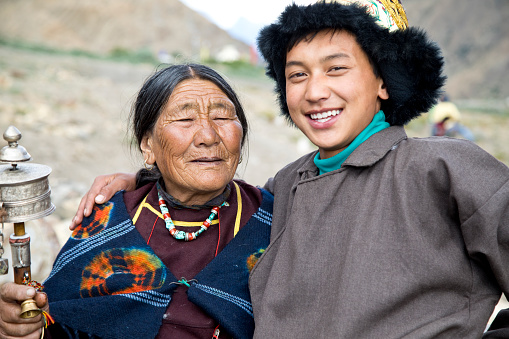 Portrait of young boy with grandmother holding hand prayer wheel