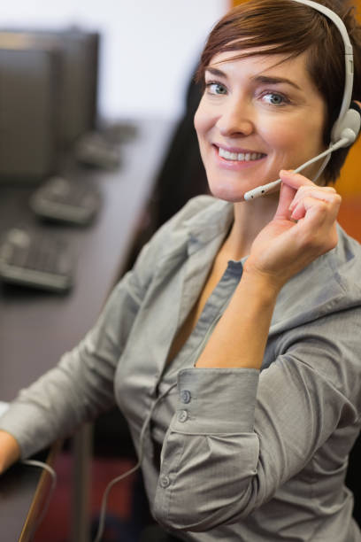 istock Teacher sitting at the computer room wearing a headset 827021084