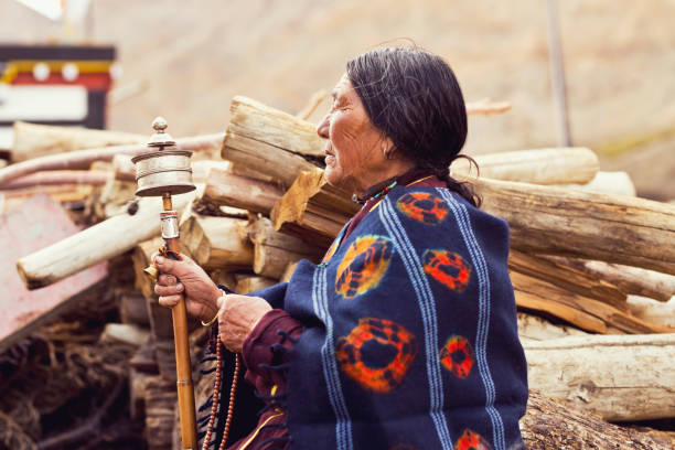 Old woman holding hand prayer wheel and prayer beads